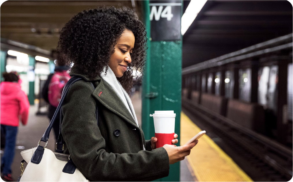 Woman standing on subway platform looking at her phone