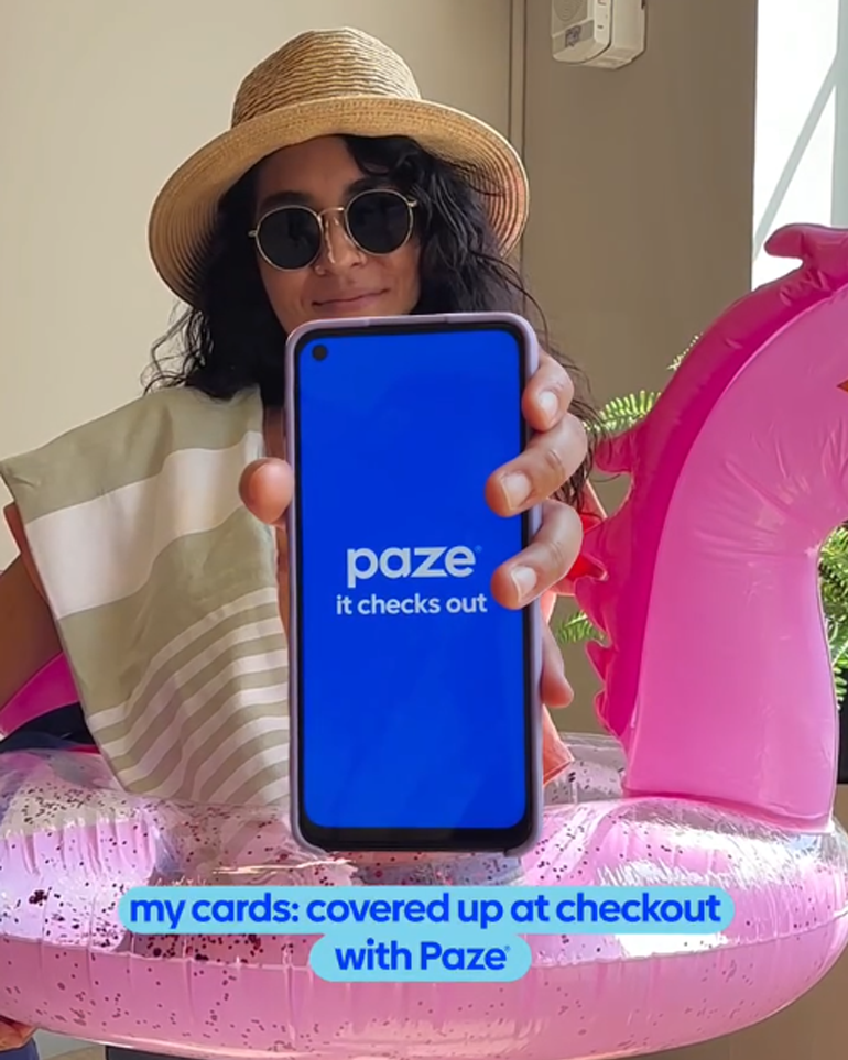 A woman wearing an inflatable pool ring showing off the Paze app on her phone.