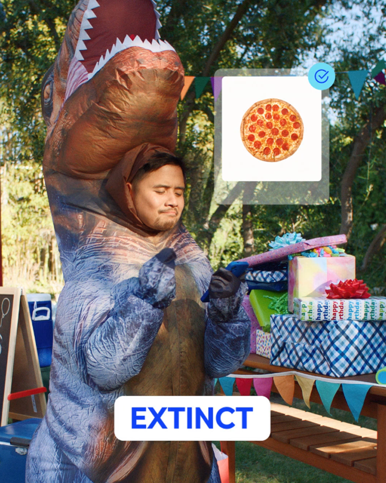 Man in t-rex costume buying pizza with paze.